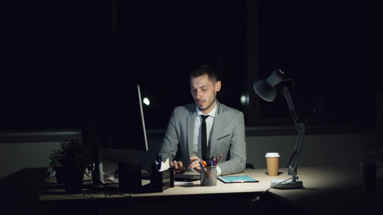 A focused businessman working late in a dimly lit office at night.